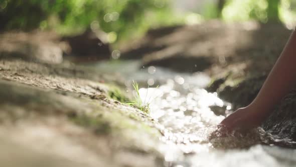 Crop woman touching flowing water in river at night alt