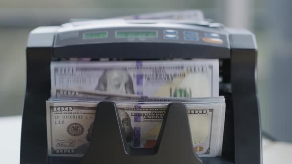 Closeup shot of money counting machine with 100 dollar bills.