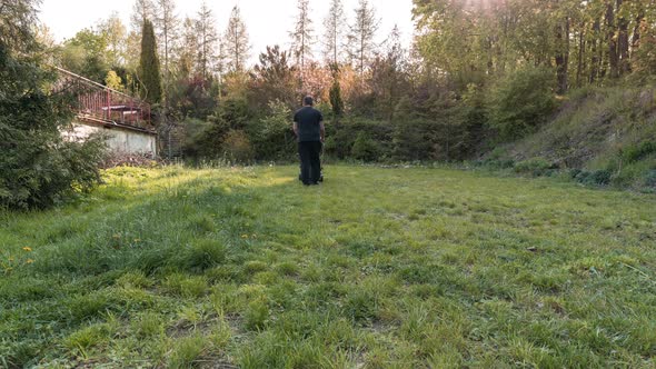 Young Caucasian Man Mowing Lawn in a Large Countryside Garden