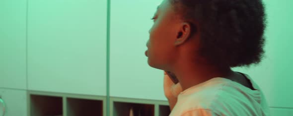 African American Woman Brushing Teeth and Talking on Phone alt