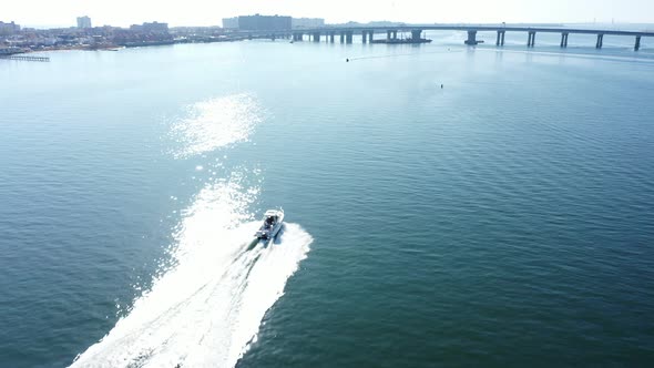 An aerial drone shot over Jamaica Bay in Queens, NY. The camera dolly in following a boat which is h alt
