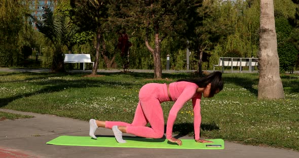 Young black woman trains, doing exercises in yoga pose of a rider outdoors.