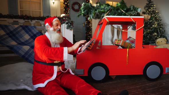 Joyous Santa Claus Enjoying with Modern Gadget.