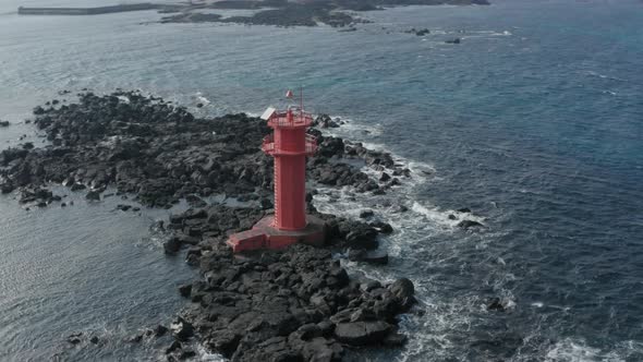 Drone view. Scenery with wild waves and red lighthouse. Arc shot. Jeju Island in korea