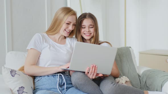 Adult Mother and Teenager Girl Daughter Child Sitting Together on Couch Using Modern Laptop Watching alt