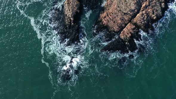 Aerial view of ocean waves splashing in rocks