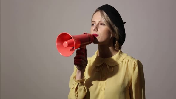 Blonde woman in hat and yellow dress speaking in loudspeaker