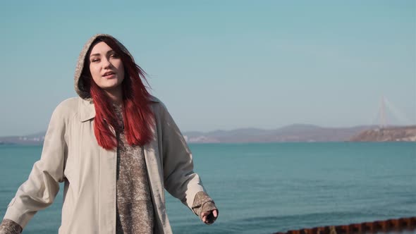 one girl in a coat stands on the shore of a calm sea