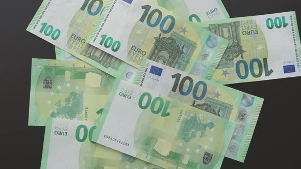 Hand Throwing 100 One Hundred Euro Currency Banknotes on Black Background Table alt