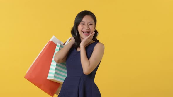 Excited surprised Asian woman carrying shopping bags
