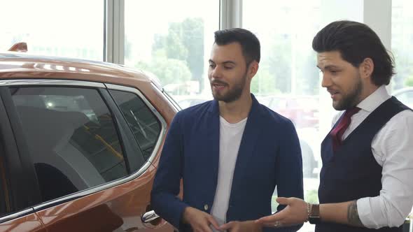 Two Male Friends Discuaaing a New Car at the Dealership Salon alt