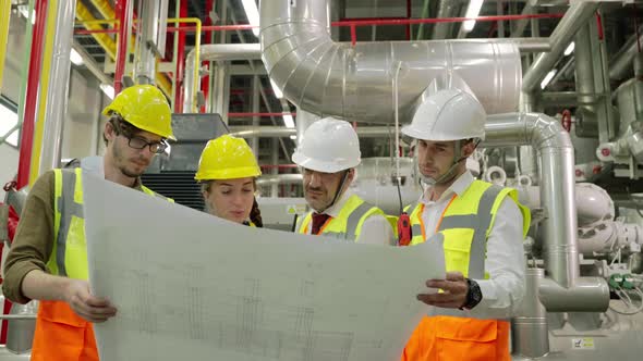 Engineerc and Foreman are discussing the plant layout on the blueprint in the factory boiler room