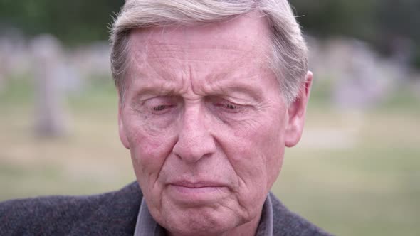 View of elderly mans face as he stares towards the ground alt