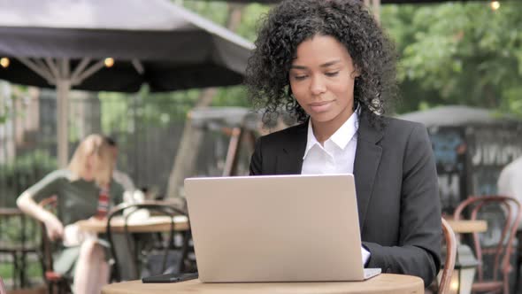 African Businesswoman Sitting in Outdoor Café and Using Laptop alt