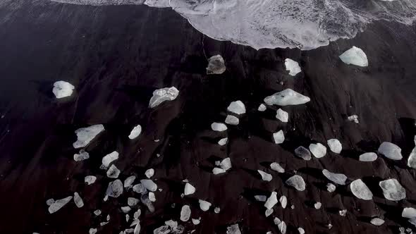 Aerial view of black sand beach with iceberg ice pieces on the shore also cal