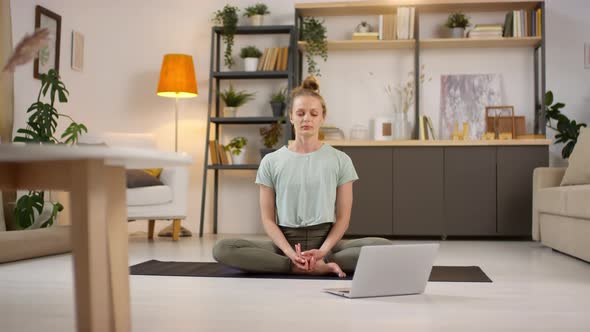 Woman Meditating at Home during Online Yoga Class alt