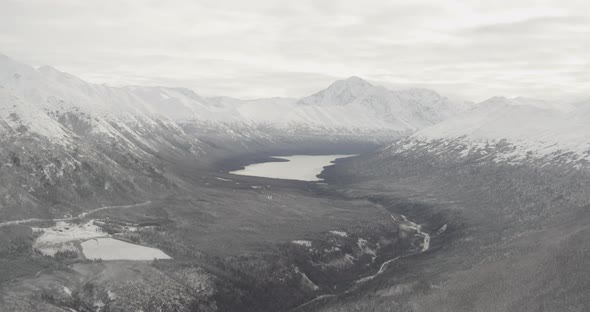 Aerial helicopter flyover of Alaskan river, passing mountains, drone footage alt
