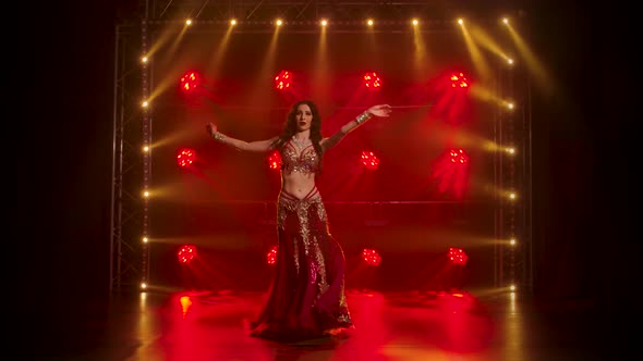 Woman in Exotic Costume Performs a Belly Dance Moves Semi Nude Body. Shot in a Dark Studio with alt