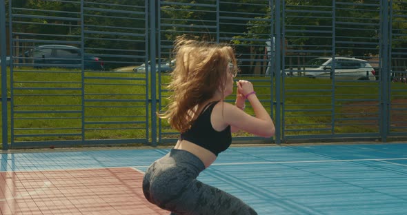 A Sporty Girl is Doing Squats with Jumping Out and Jumping on Different Legs alt