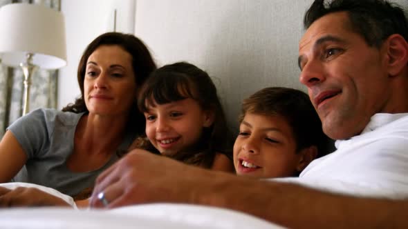 Parents and kids using laptop on bed in bedroom alt