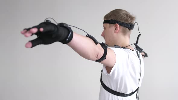 Athletic Man with Beard Wears Motion Capture Suit with Sensors Headset Moving in Virtual Reality