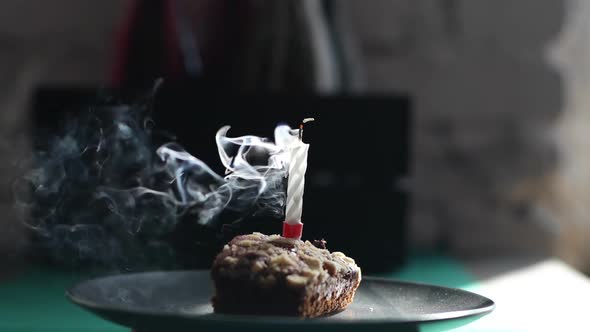 Close-up of Blowing Out Candle on Festive Cupcake in Dark Room alt