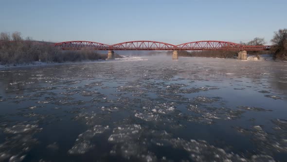 Drone Shot Flies Forward Over the Frozen River to the Red Steel Bridge Aerial View  Video Footage