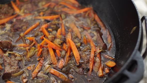 Stewing Carrots with Meat in Fat for Uzbek Pilaf in a Cauldron alt