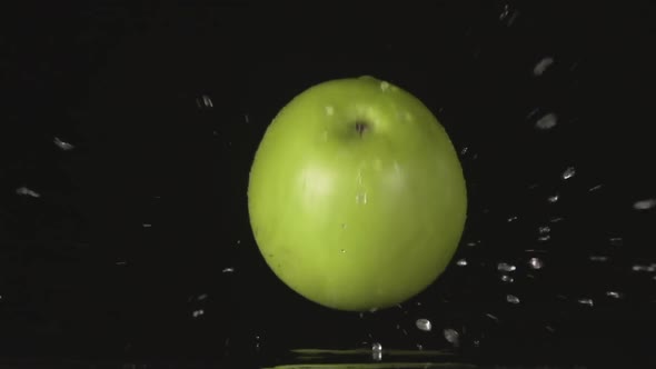 Green Apple Falls On A Black Background