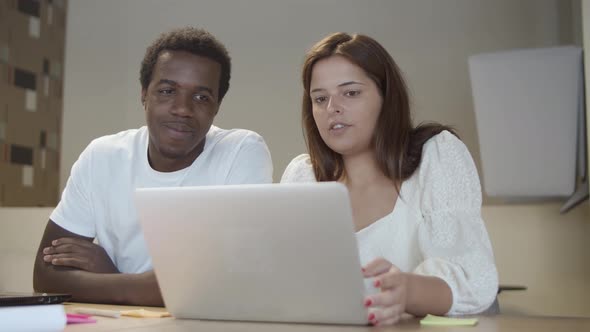 Couple of Startup Managers Sitting at Table with Laptop alt