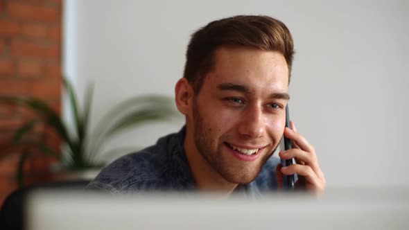 Closeup Face of Positive Businessman Talking Mobile Phone at Home Office Looking on Laptop Screen alt