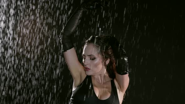 Portrait of a Beautiful Busty Woman in a Black Suit Posing Against a Dark Background While Raindrops alt