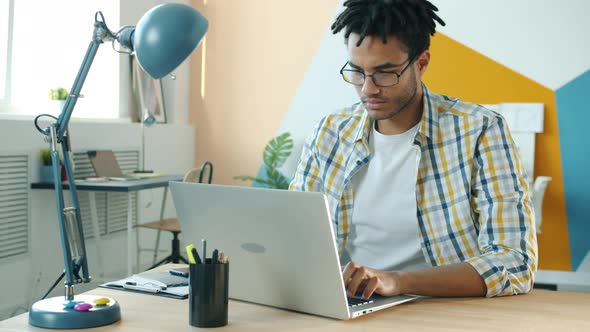 Serious Mixed Race Businessman Using Laptop Computer Typing at Desk in Workplace alt