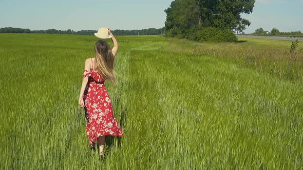 Slow Motion Young Girl Runs Across Green Field in Red Dress That Flutters in the Wind She Takes Off alt