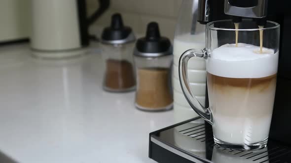 Cappuccino From the Coffee Machine Is Poured Into a Glass Cup alt