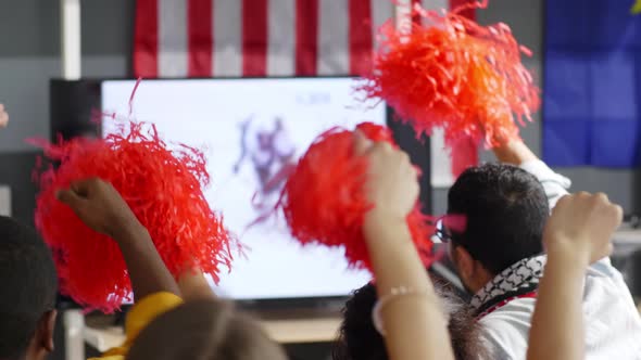 Fans with pom-poms watching ice hockey at home