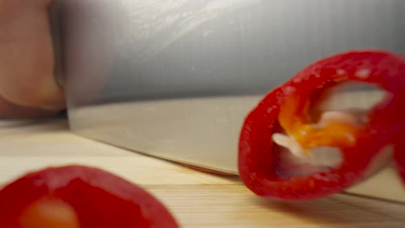 Male Hands Slicing Red Hot Chili Pepper with Sharp Knife on Black Background alt