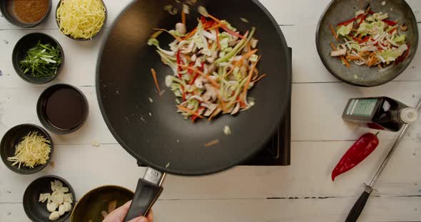 Chef Holding Frying Pan and Falling Wok Noodles with Many Different Veggies alt