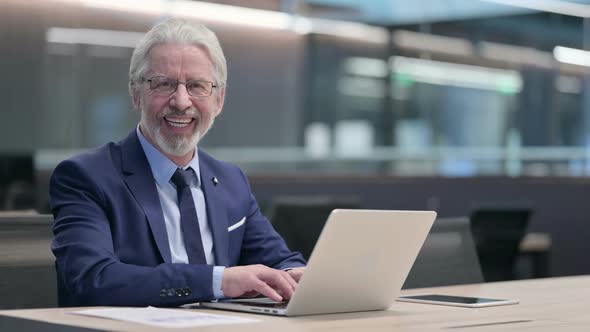 Thumbs Up By Old Businessman with Laptop at Work alt
