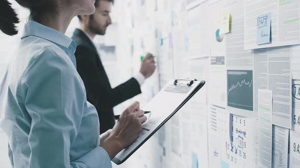 Business people checking financial data on a wall