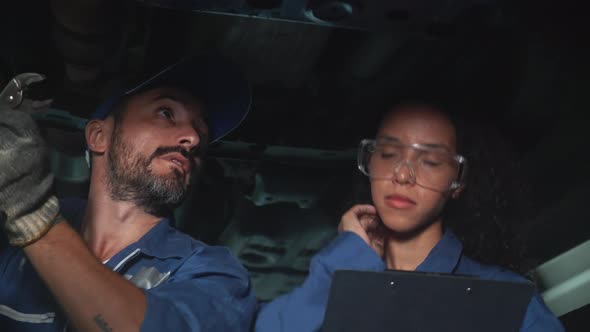 Mechanic team with man repair and woman hold clipboard diagnostics car in the garage. alt