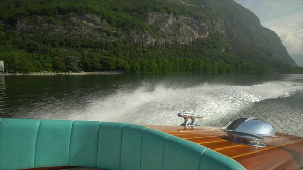 Water spray comes from a classic luxury wooden runabout boat on an Italian lake. alt