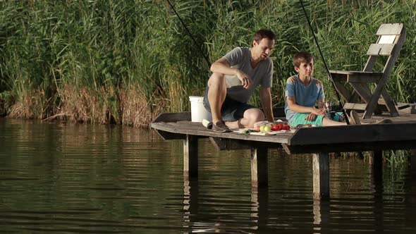 Fishermen Having Breakfast on Wooden Pier at Pond alt