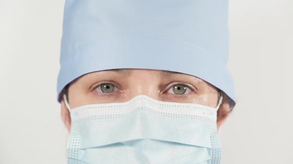 female medic in a disposable mask and textile cap  alt