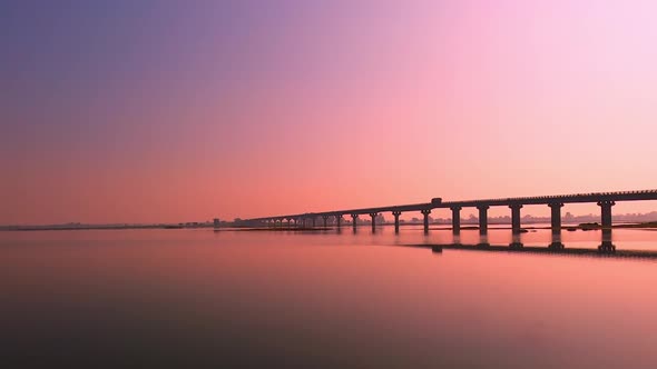 A truck moving on the bridge over a river during a beautiful evening alt