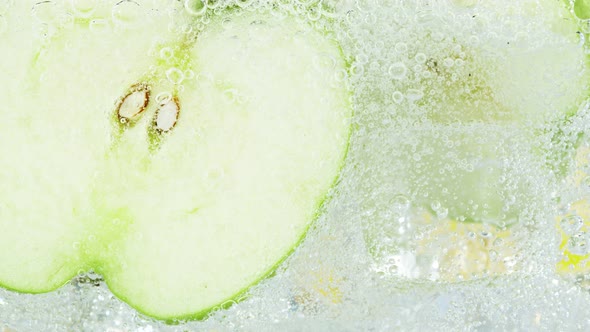 Super Slow Motion Shot of Fizzing Water with Apple Slices and Ice Cubes in Glass at 1000 Fps alt