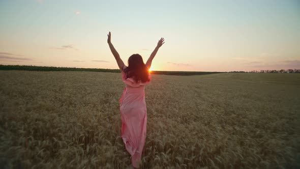 A Girl in a Dress Runs Through a Wheat Field at Sunset alt