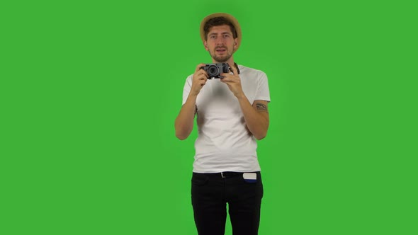 Tourist in Hat on Vacation Takes Pictures on a Retro Camera. Green Screen alt