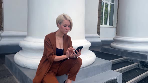 Young Blonde Business Lady Uses Smartphone