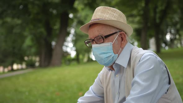 Old Man in a Medical Mask Sitting in the Park alt